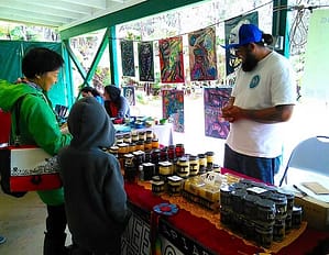 Farmers Market Sunday A vendor sells handcrafted goods to a family at Sunday Farmer's Market in Volcano.