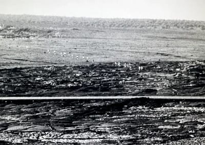 Archival photo of a line of people hiking across a volcanic crater.